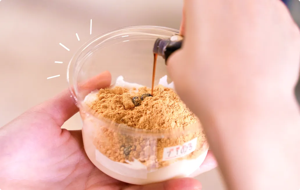 酒菜 谷の牛乳豆腐屋の牛乳豆腐にきな粉と黒蜜をかけている様子